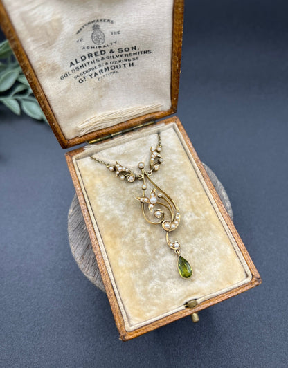 A yellow gold floral pendant necklace with pearls and a peridot drop, in an antique box