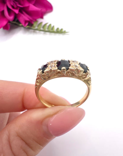 A seven stone sapphire and diamond carved ring in yellow gold, held in a hand