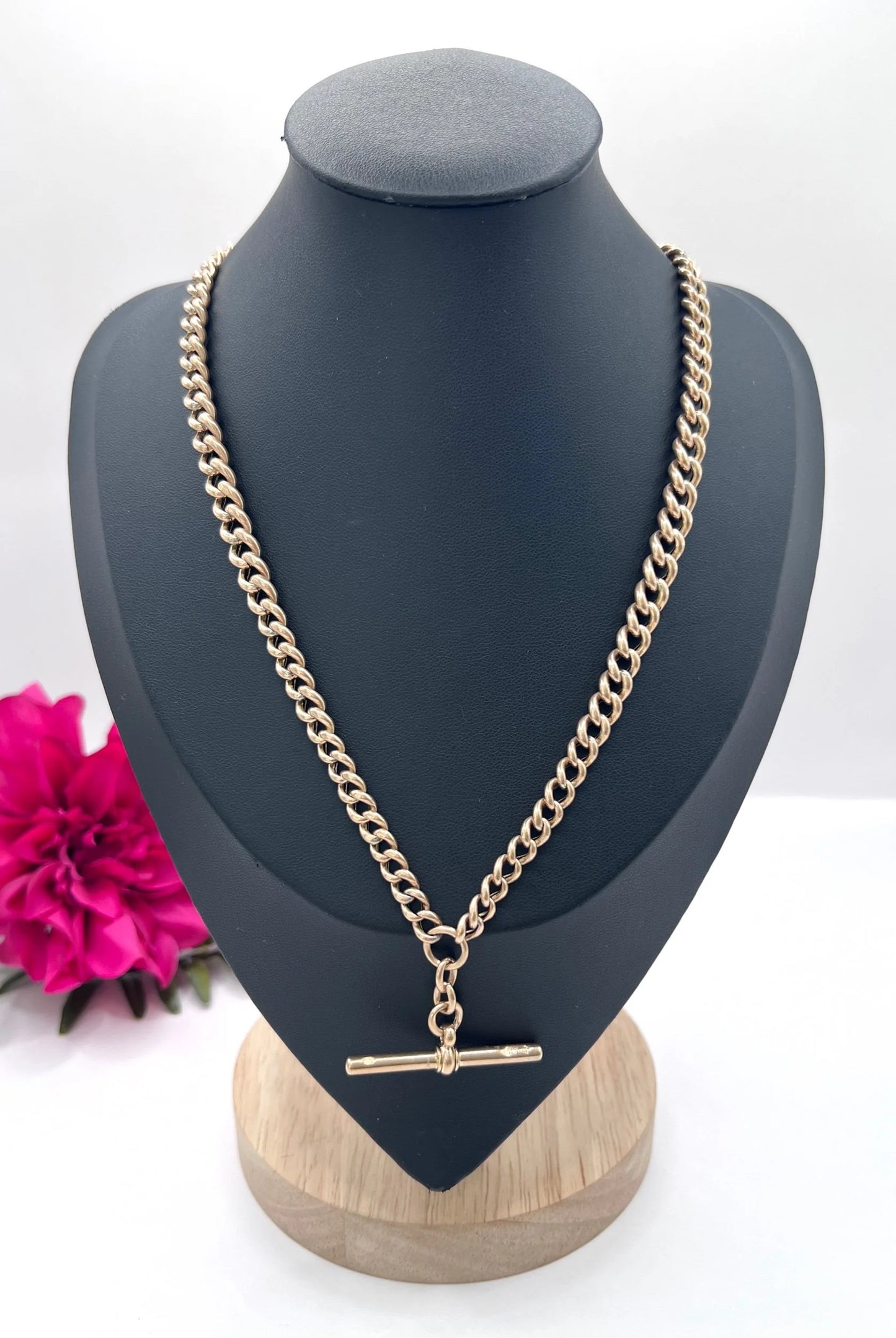 A rose gold curb link Albert chain with t-bar, on a black jewellery bust