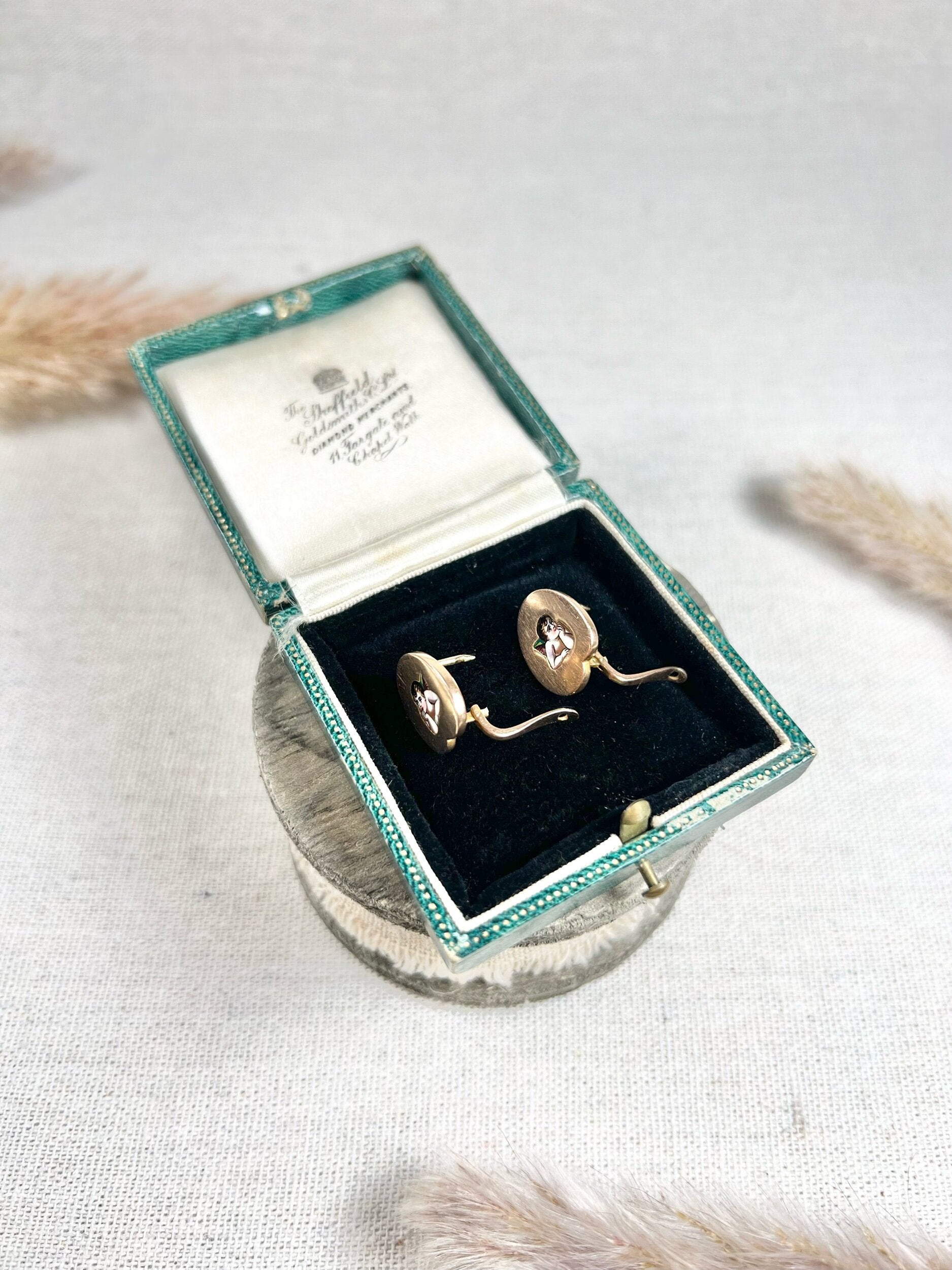 A pair of art palette shaped gold earrings with enamelled cherubs, in a box