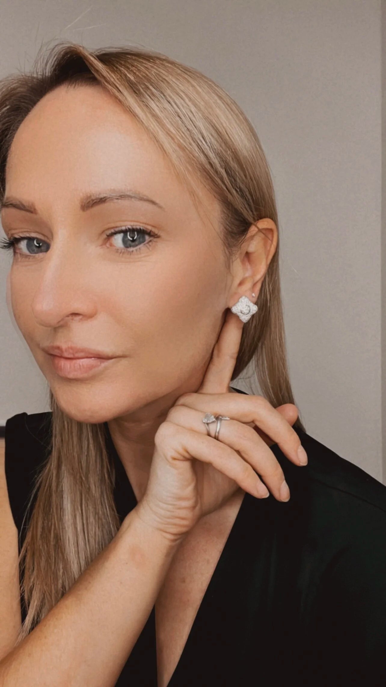 A diamond cluster stud earring, modelled by a woman wearing a black top