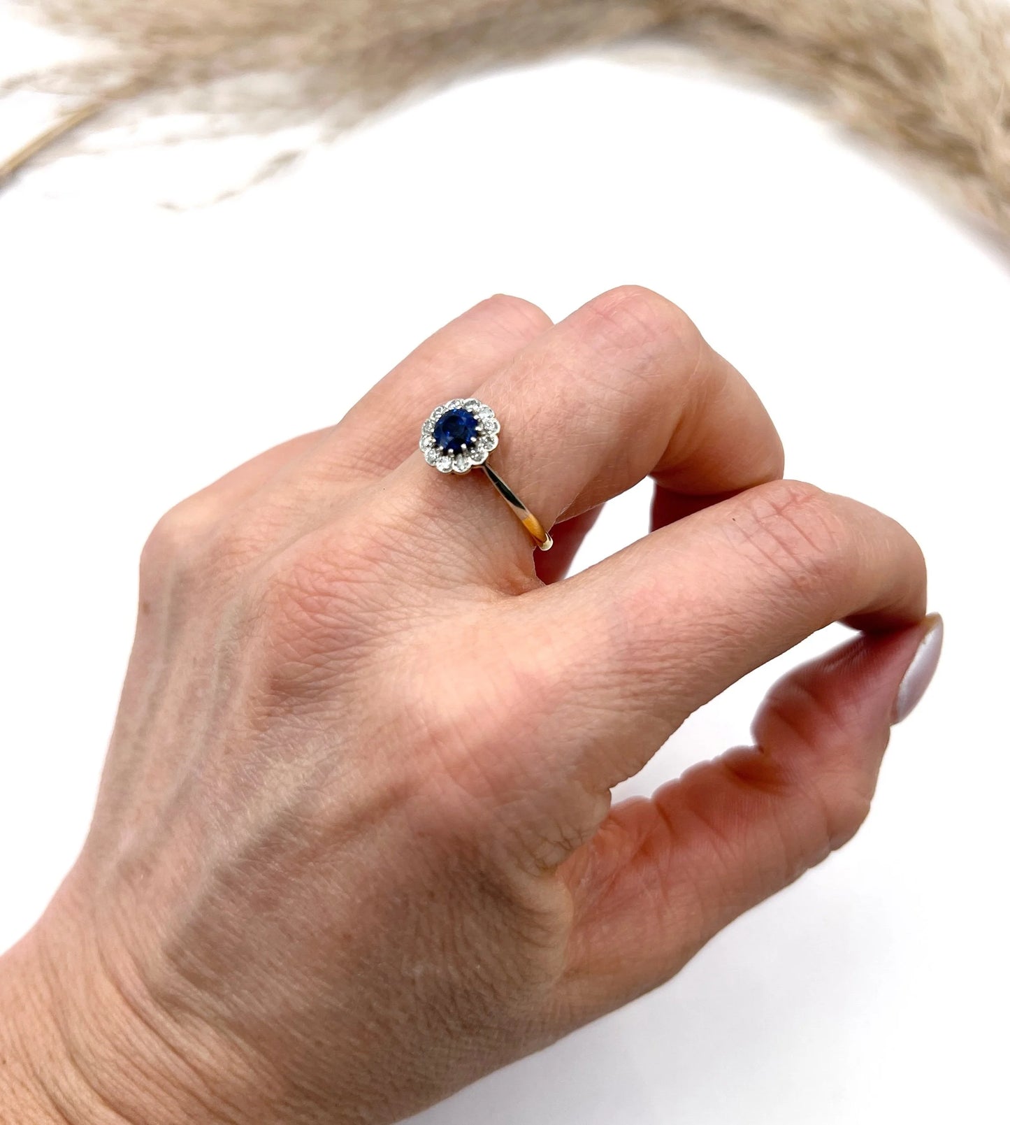 A sapphire and diamond flower cluster ring in yellow gold and platinum, modelled on a hand