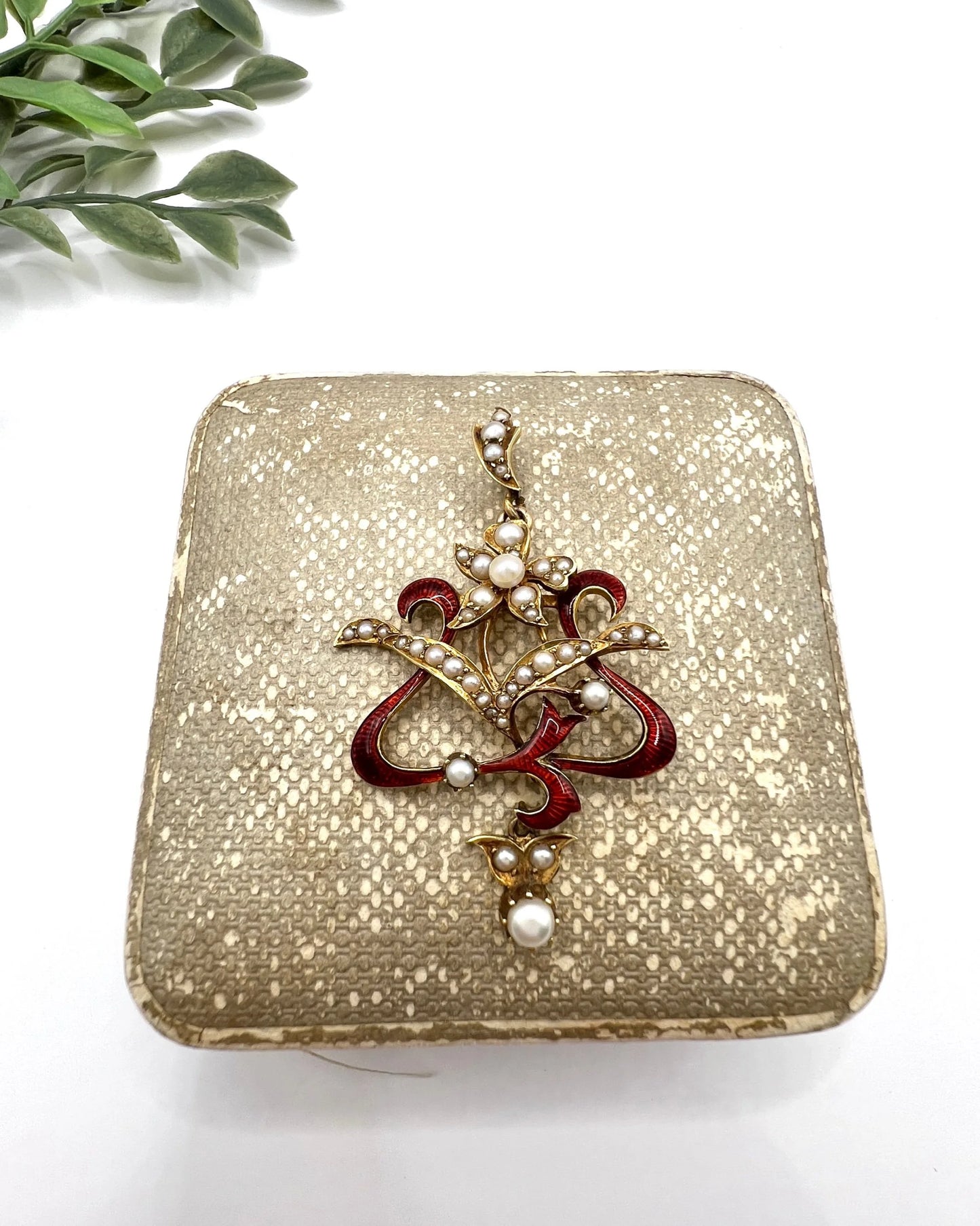 A floral pendant in yellow gold with seed pearls and red enamel