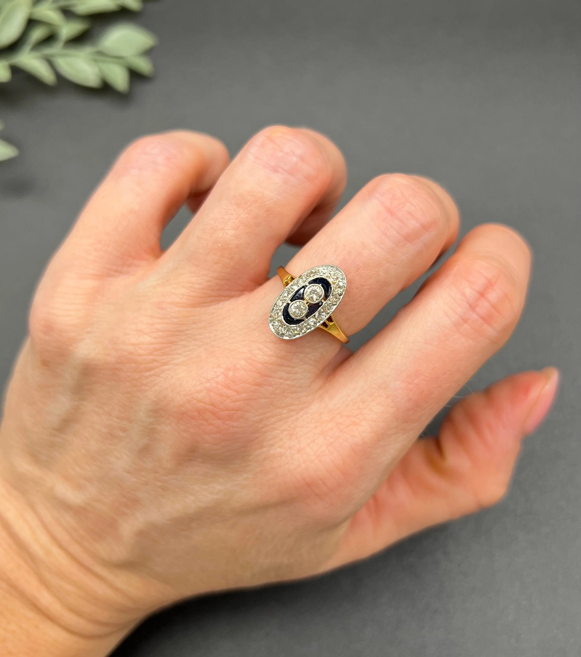 An oval cluster ring with diamonds and sapphires in platinum and yellow gold, modelled on a hand