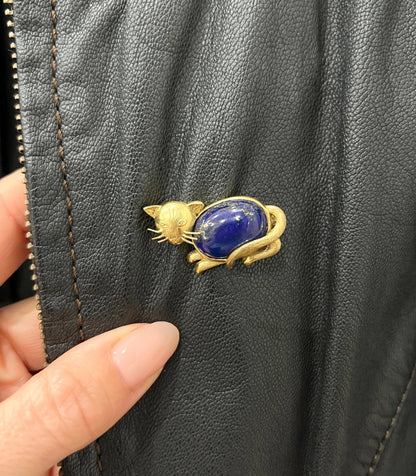 A yellow gold cat brooch with a lapis lazuli body, modelled on a black jacket