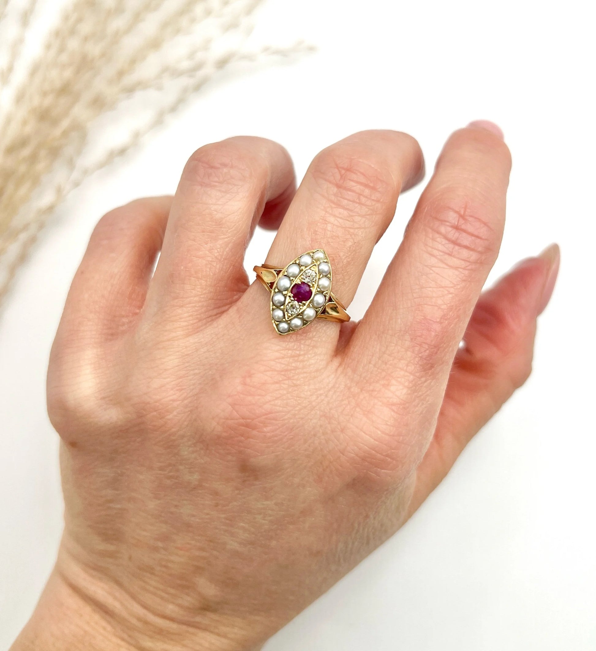 A navette shaped pearl, diamond and ruby cluster ring in yellow gold, modelled on a hand