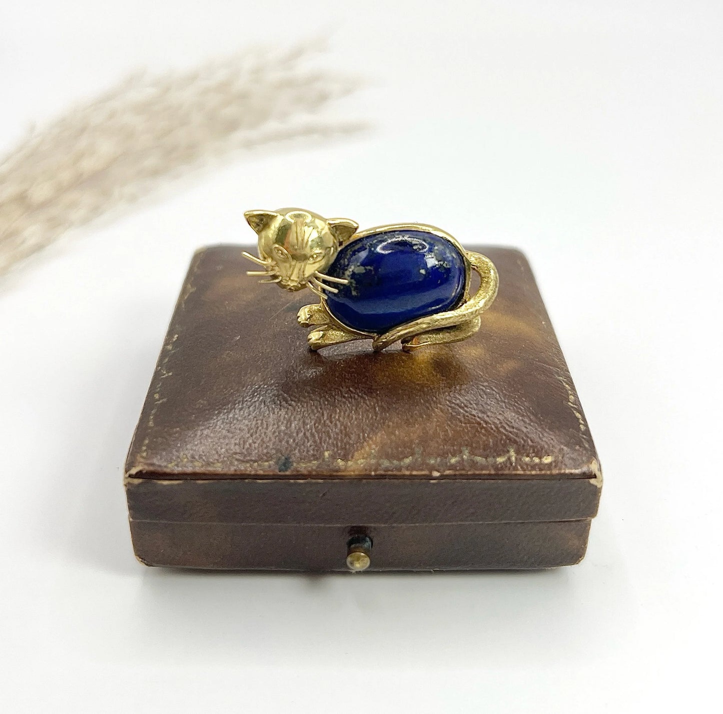A yellow gold cat brooch with a lapis lazuli body