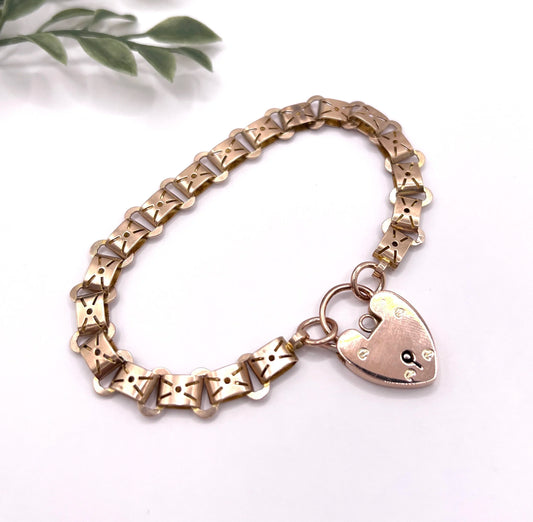 A rose gold fancy link bracelet with a heart shaped padlock clasp