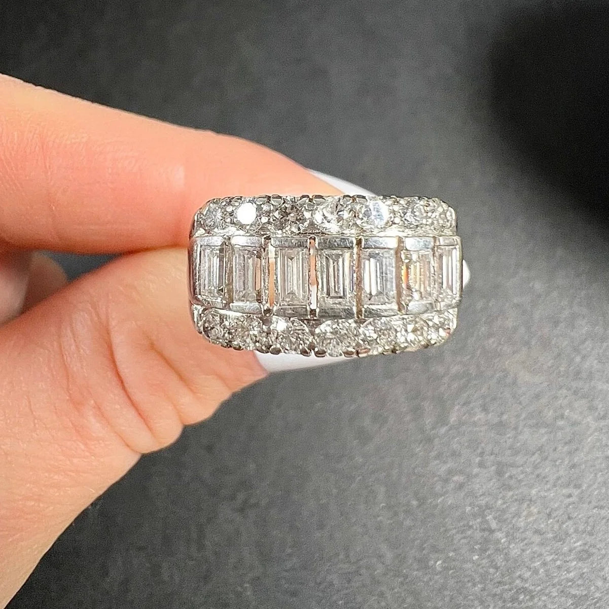 A three row diamond band ring in platinum held in a hand