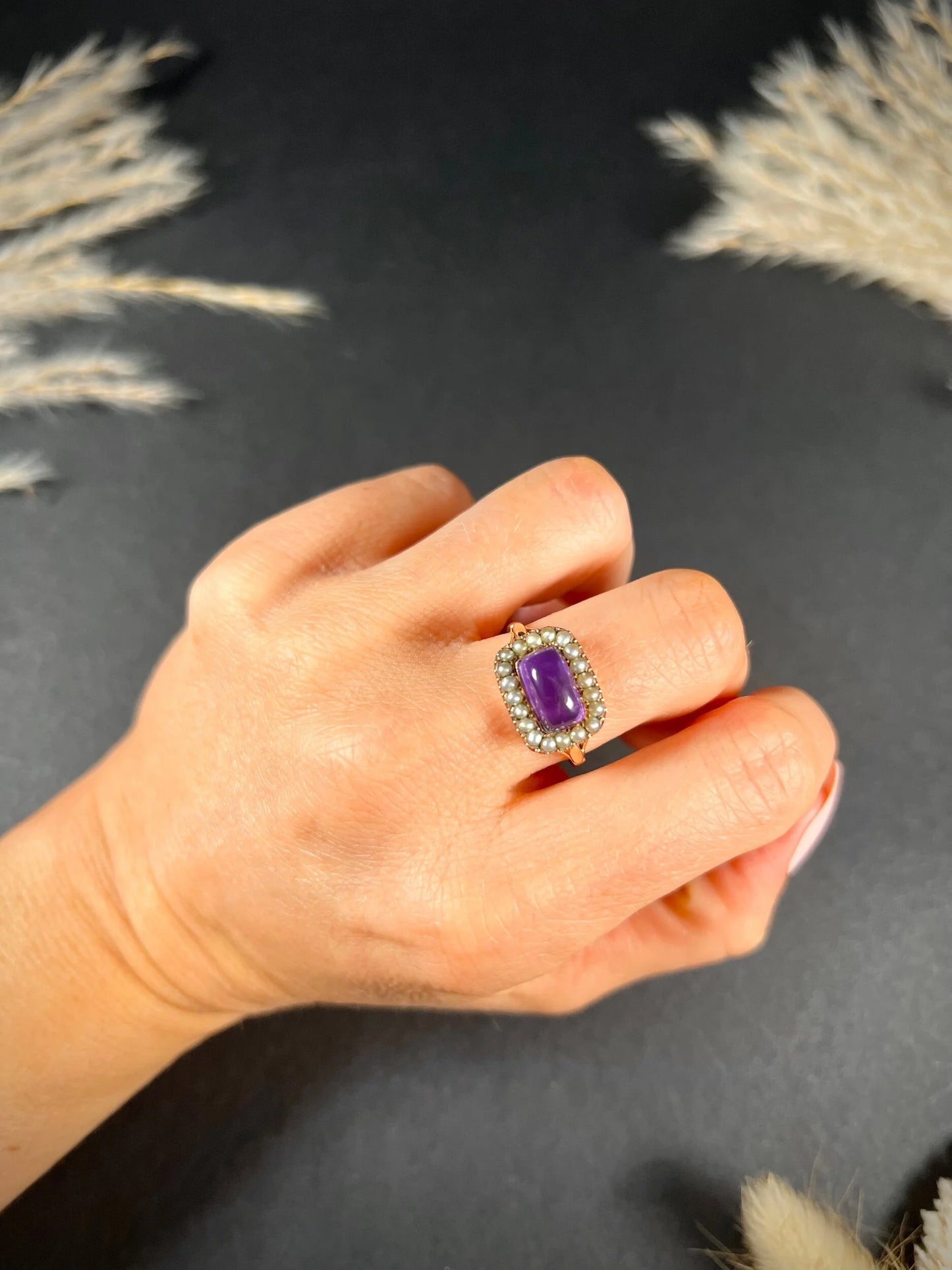A cabochon amethyst and pearl halo cluster ring in gold, modelled on a hand