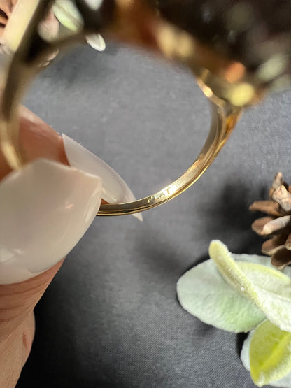 A close-up of a PLAT stamp inside a gold ring shank, held in a hand