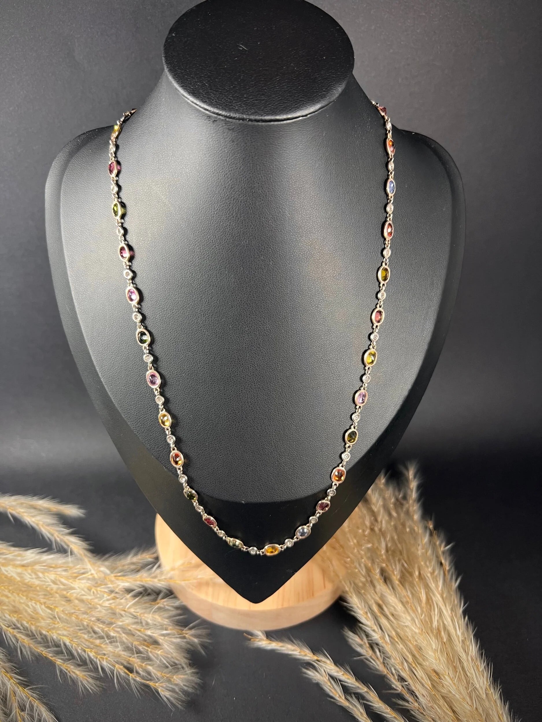 A coloured sapphire and diamond set necklace in platinum and gold, modelled on a black jewellery bust