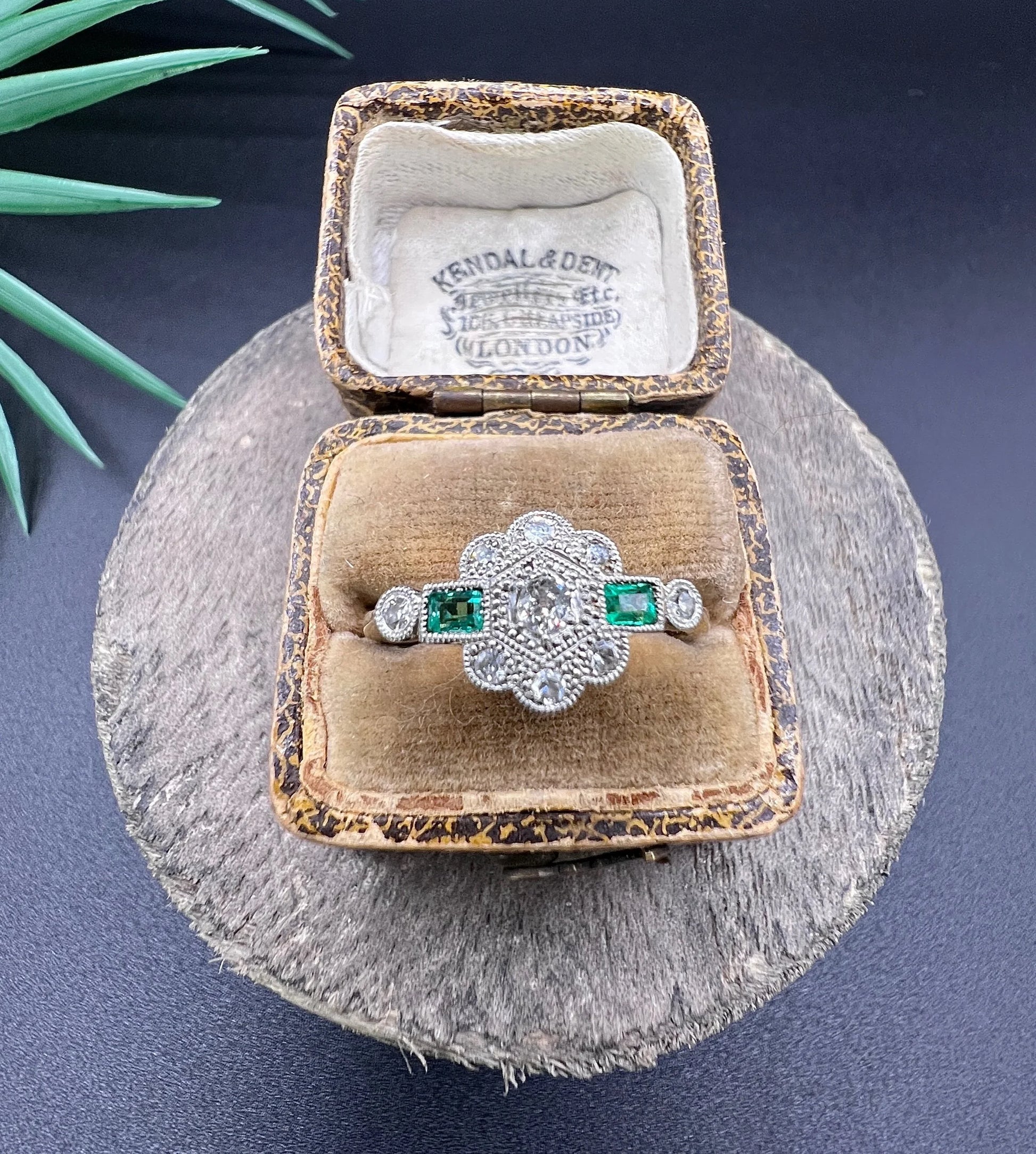 An emerald and diamond floral cluster ring in yellow gold and platinum, in an antique ring box