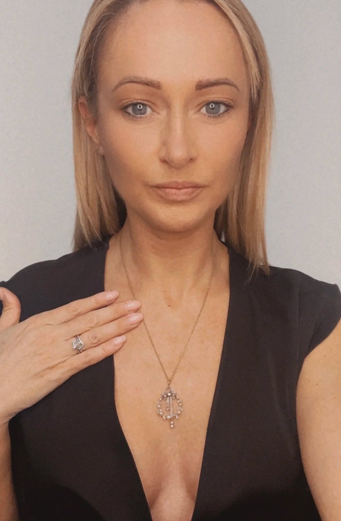 A pearl and diamond bow pendant in gold and platinum, with a chain, modelled by a woman