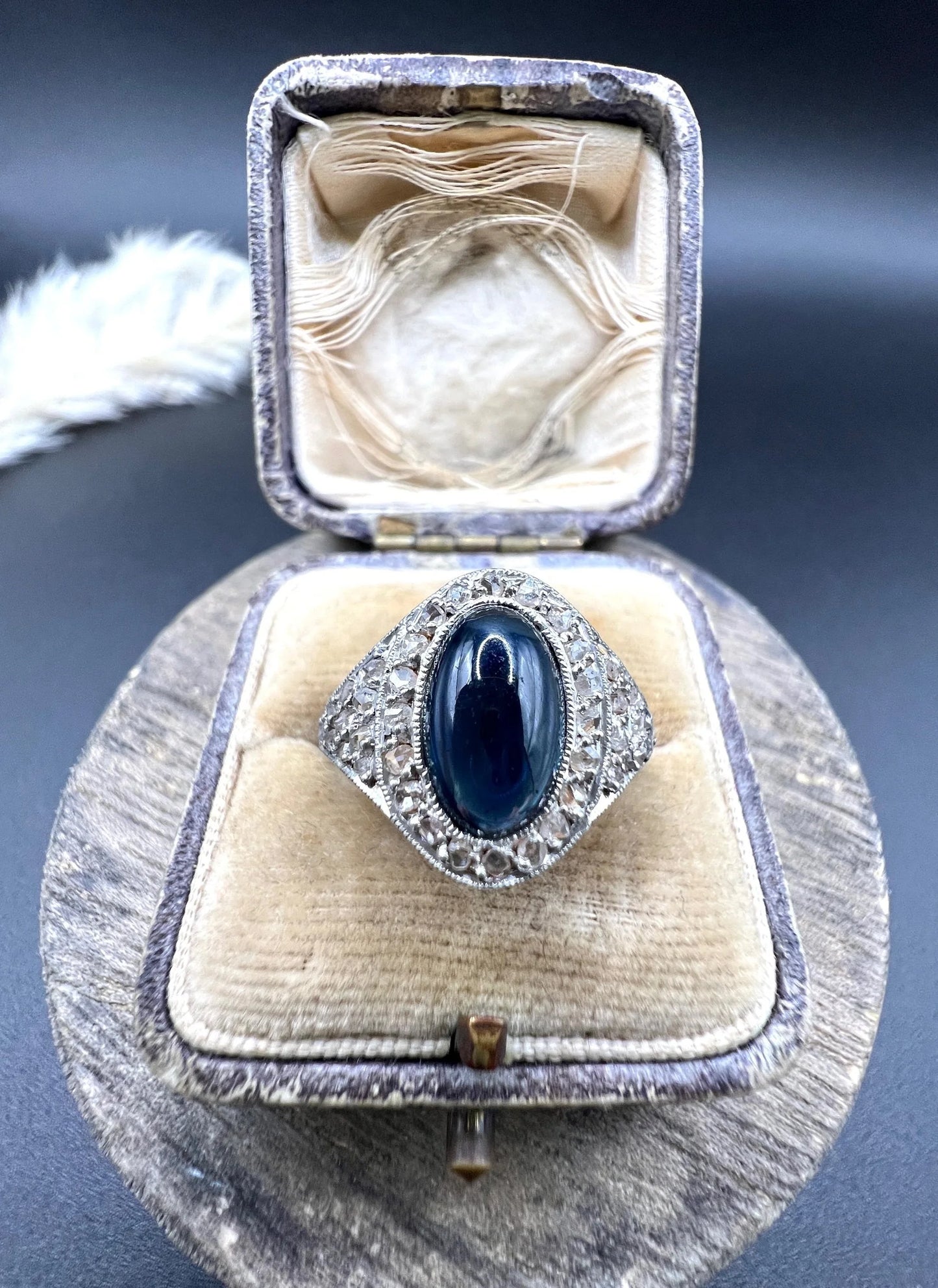 An oval cabochon sapphire and diamond fancy cluster ring in yellow and white gold, in a ring box