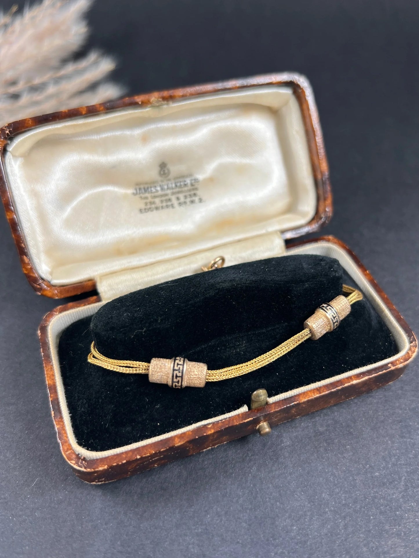 A yellow gold double row bracelet with black enamel tubular beads, in an antique box