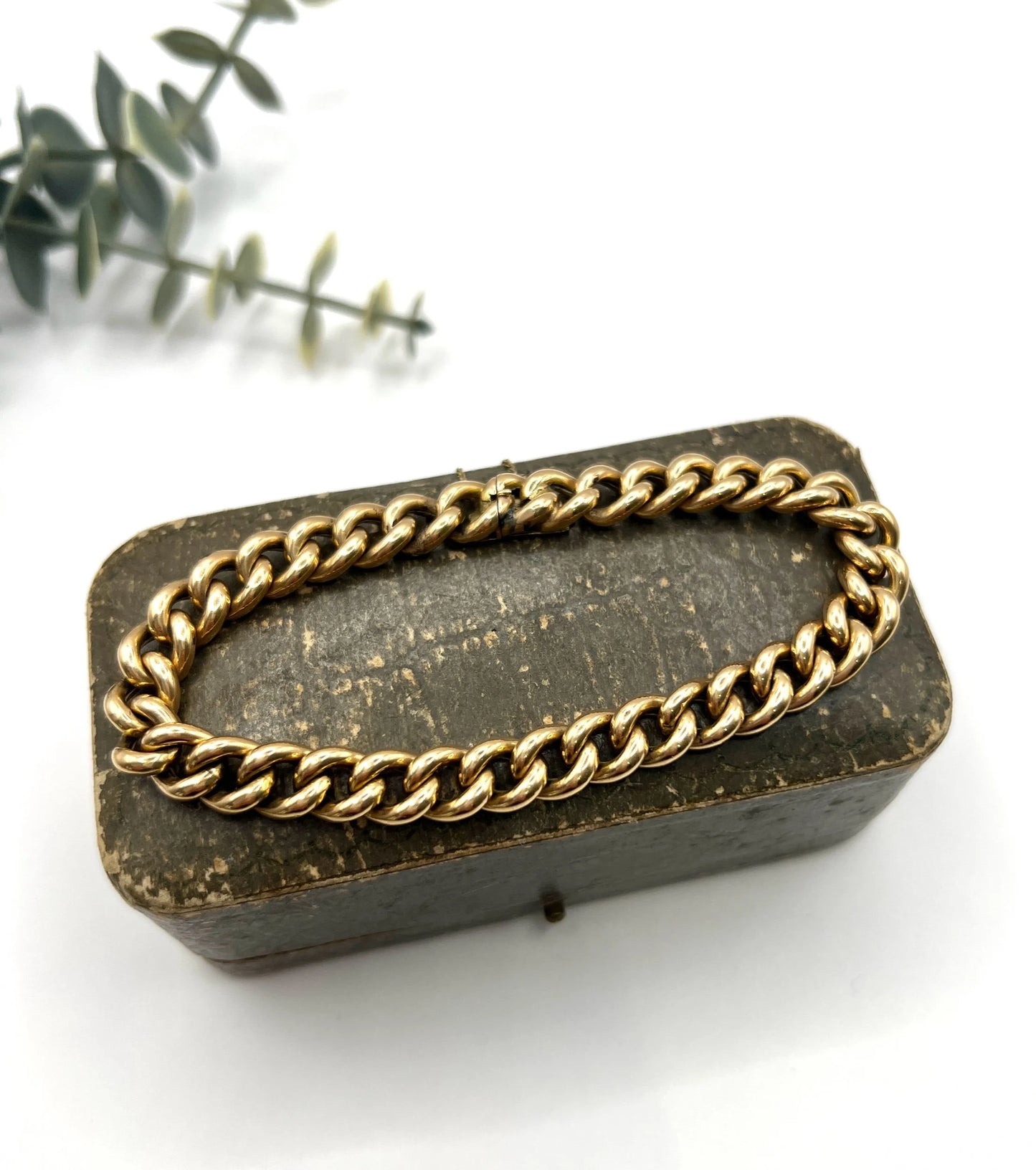 A curb link bracelet in yellow gold, on an antique box