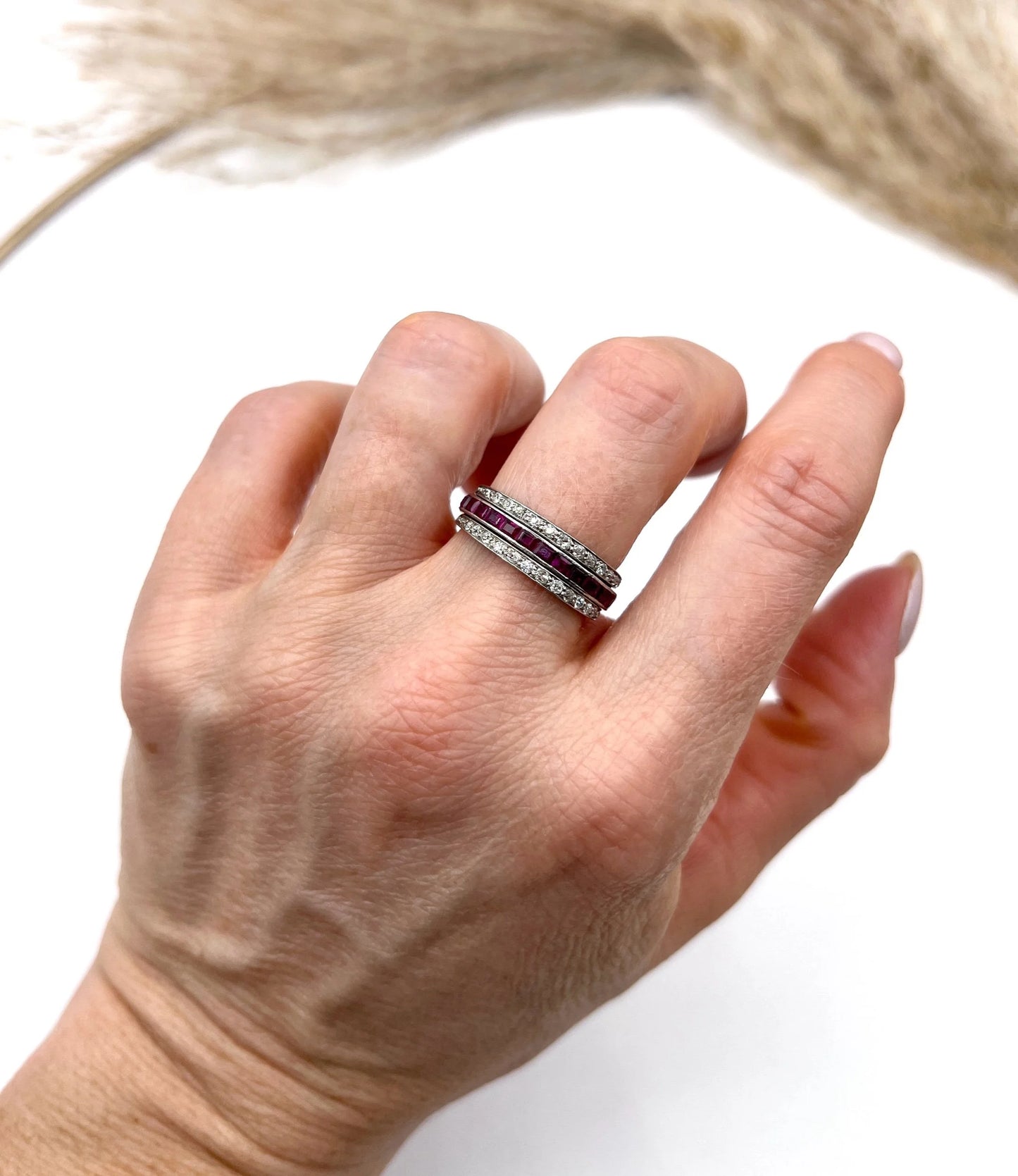 A platinum night and day flip band ring set with diamonds, sapphires and rubies, modelled on a hand