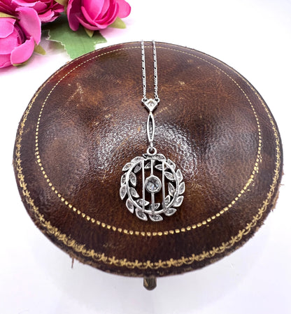 A platinum floral wreath pendant with diamonds on a platinum chain