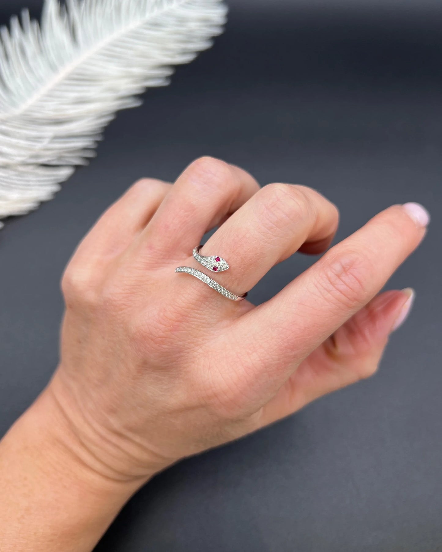 A white gold snake ring set with diamonds and with ruby eyes, modelled on a hand