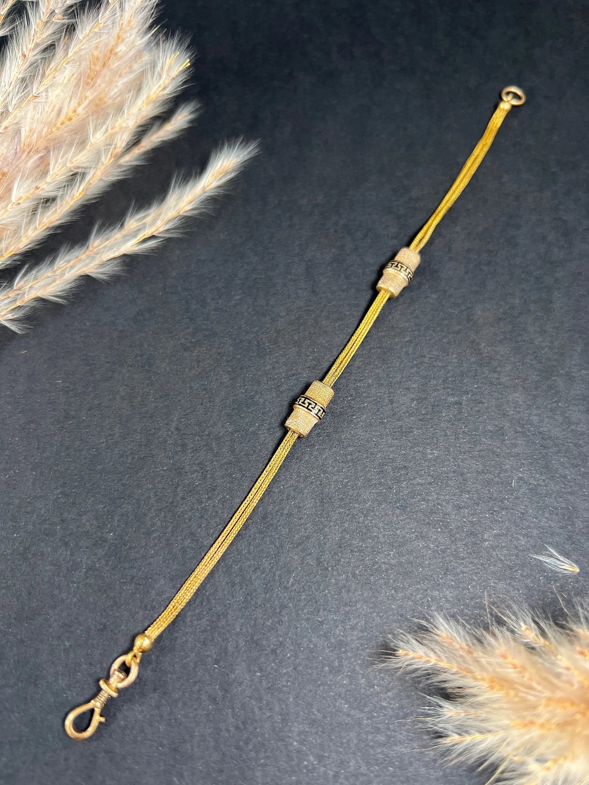 A yellow gold double row bracelet with black enamel tubular beads
