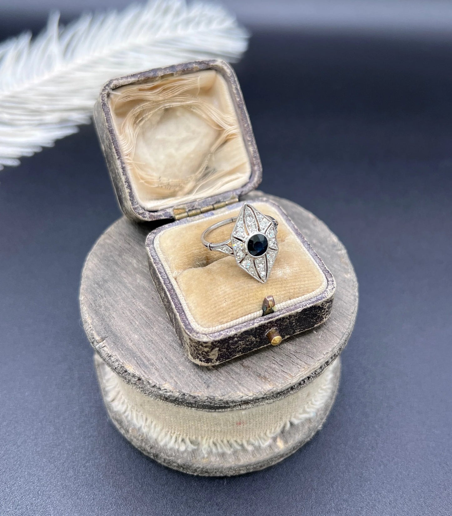 A navette shaped cluster cocktail ring with a sapphire centre surrounded by diamonds, in platinum, in an antique ring box