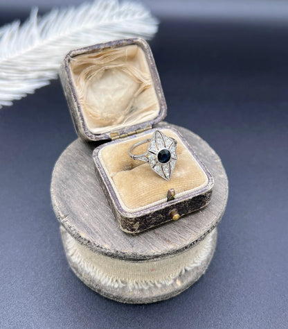 A navette shaped cluster cocktail ring with a sapphire centre surrounded by diamonds, in platinum, in an antique ring box