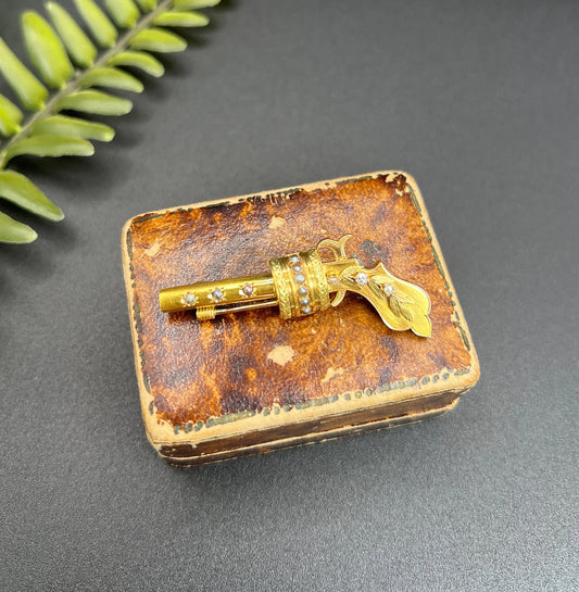 A yellow gold novelty gun brooch with diamonds and seed pearls