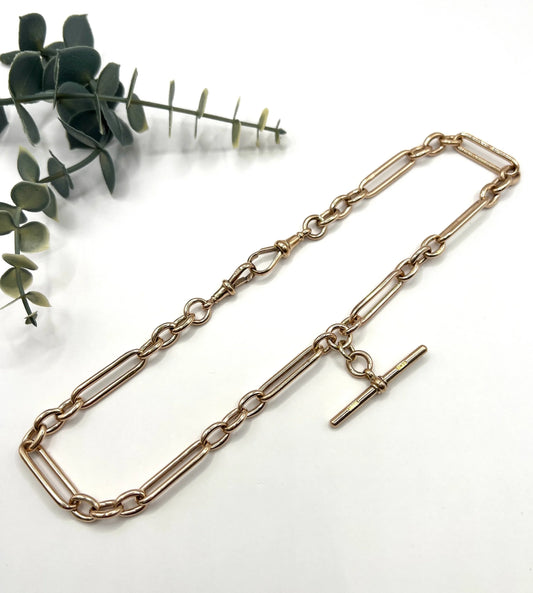 A rose gold trombone and fetter link Albert chain, on a white background