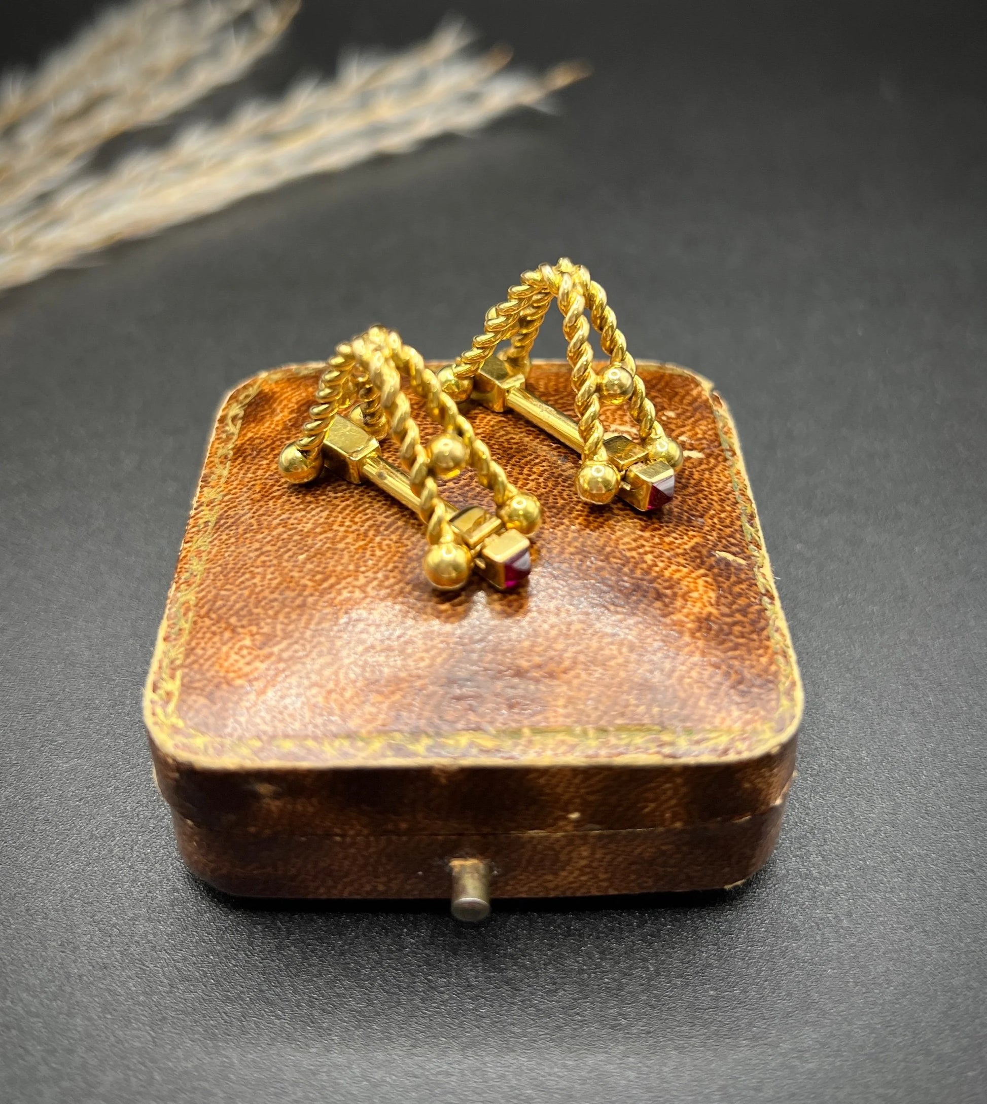 A pair of yellow gold ruby cufflinks, on an antique box