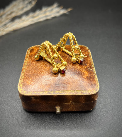 A pair of yellow gold ruby cufflinks, on an antique box