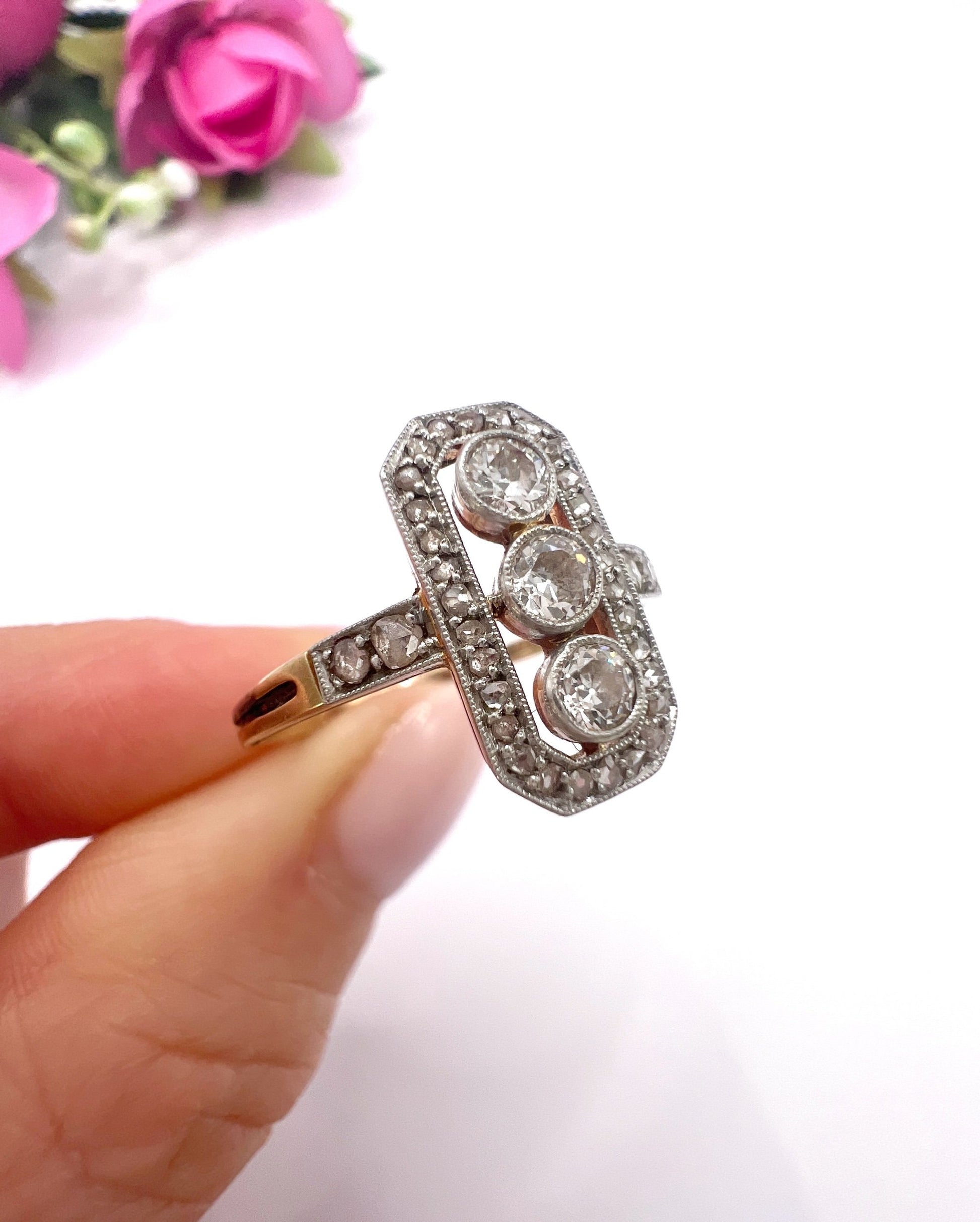 A diamond open cluster ring with three principal diamonds, in yellow and white gold, held in a hand