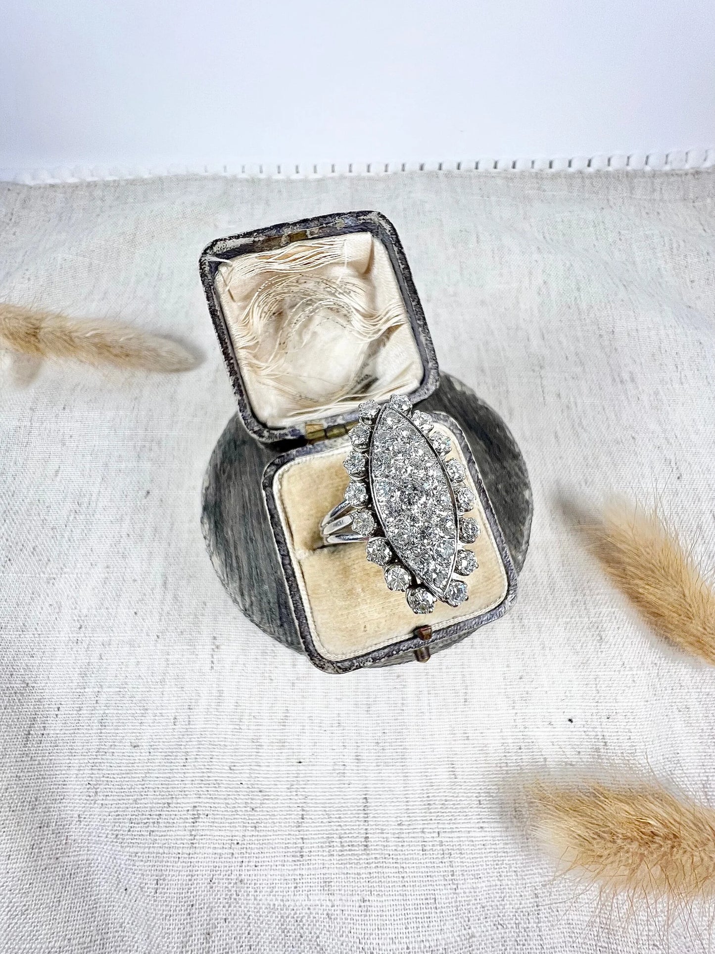 A navette shaped diamond cluster ring in white metal, in an antique ring box