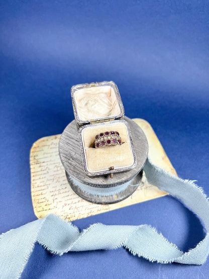 A yellow gold triple row ring with garnets and seed pearls, in a ring box