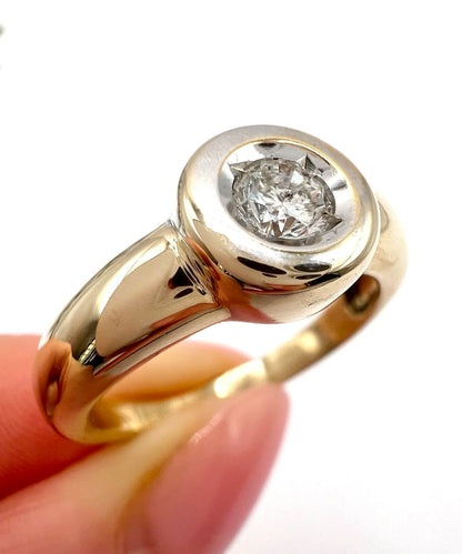 A single stone brilliant cut diamond ring bezel set in yellow gold, close-up