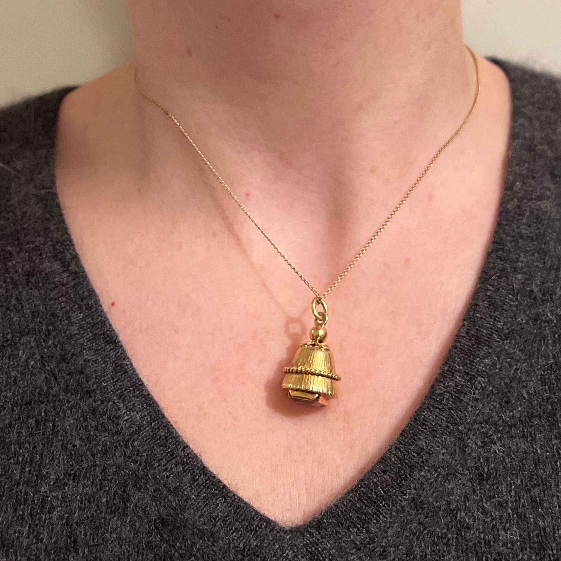 A yellow gold pendant with an amethyst set in the base, modelled on a gold chain