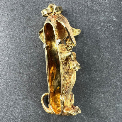 A yellow gold dachshund dog charm with ruby eyes, on a dark background