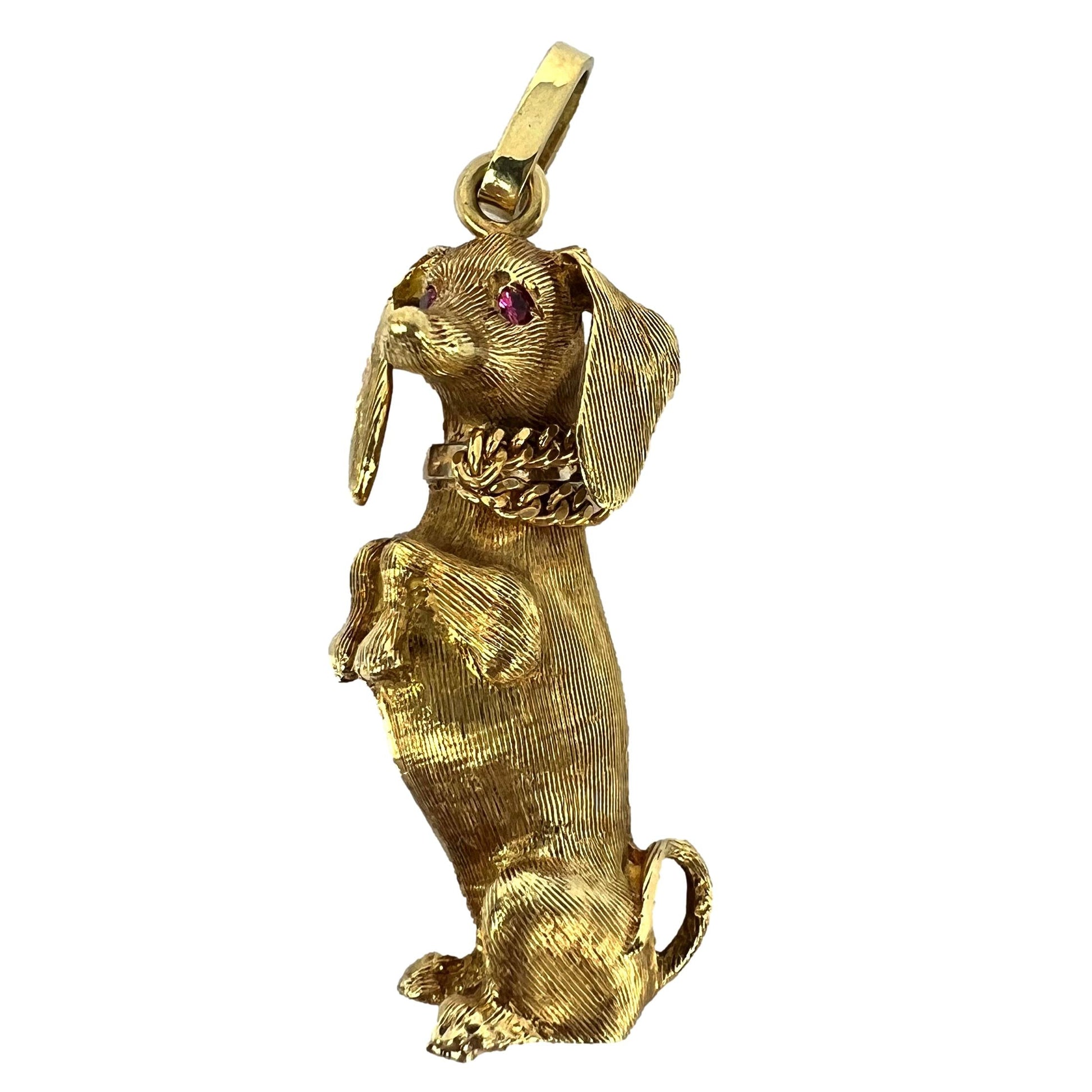 A yellow gold dachshund dog charm with ruby eyes, on a white background