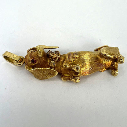 A yellow gold dachshund dog charm with ruby eyes, on a white background