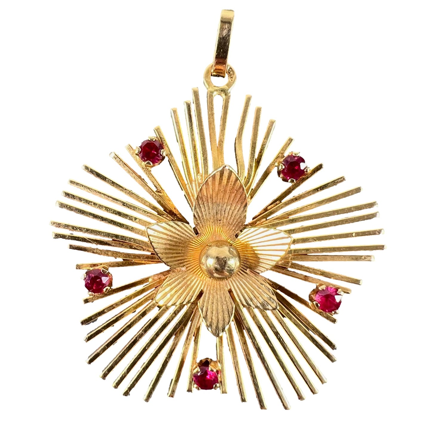 A yellow gold floral sunburst pendant with rubies, on a white background
