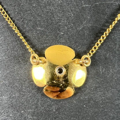 A yellow gold and diamond flower pendant necklace, on a grey background