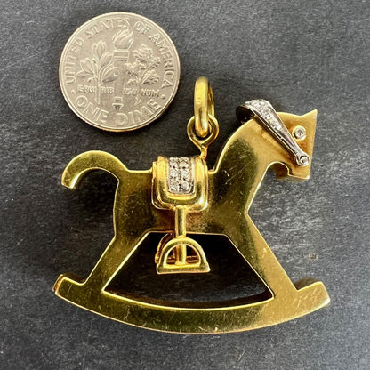 A yellow and white gold rockinghorse pendant with diamonds, next to a dime coin on a grey background