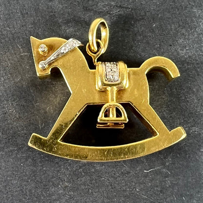 A yellow and white gold rockinghorse pendant with diamonds, on a grey background