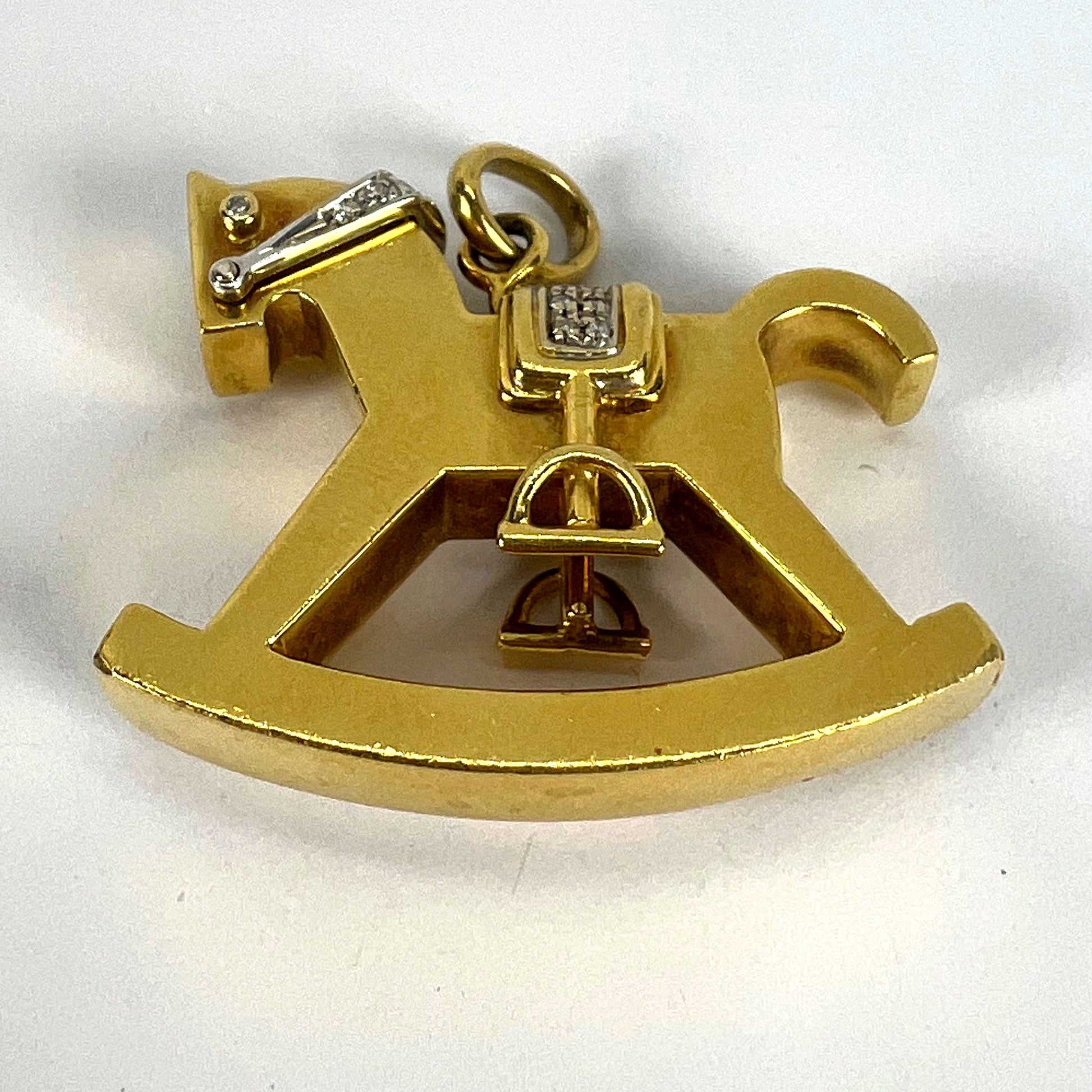 A yellow and white gold rockinghorse pendant with diamonds, on a white background
