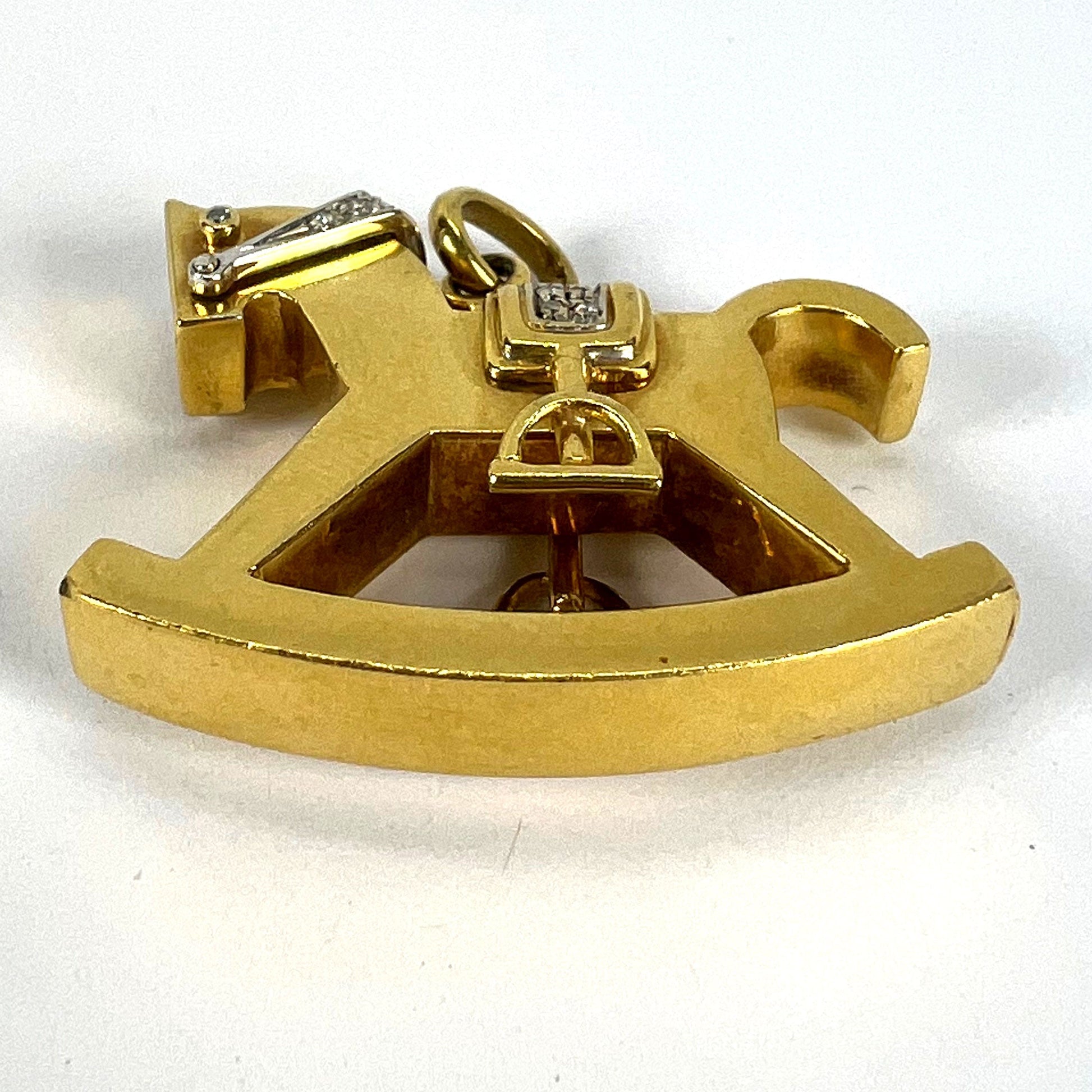 A yellow and white gold rockinghorse pendant with diamonds, on a white background