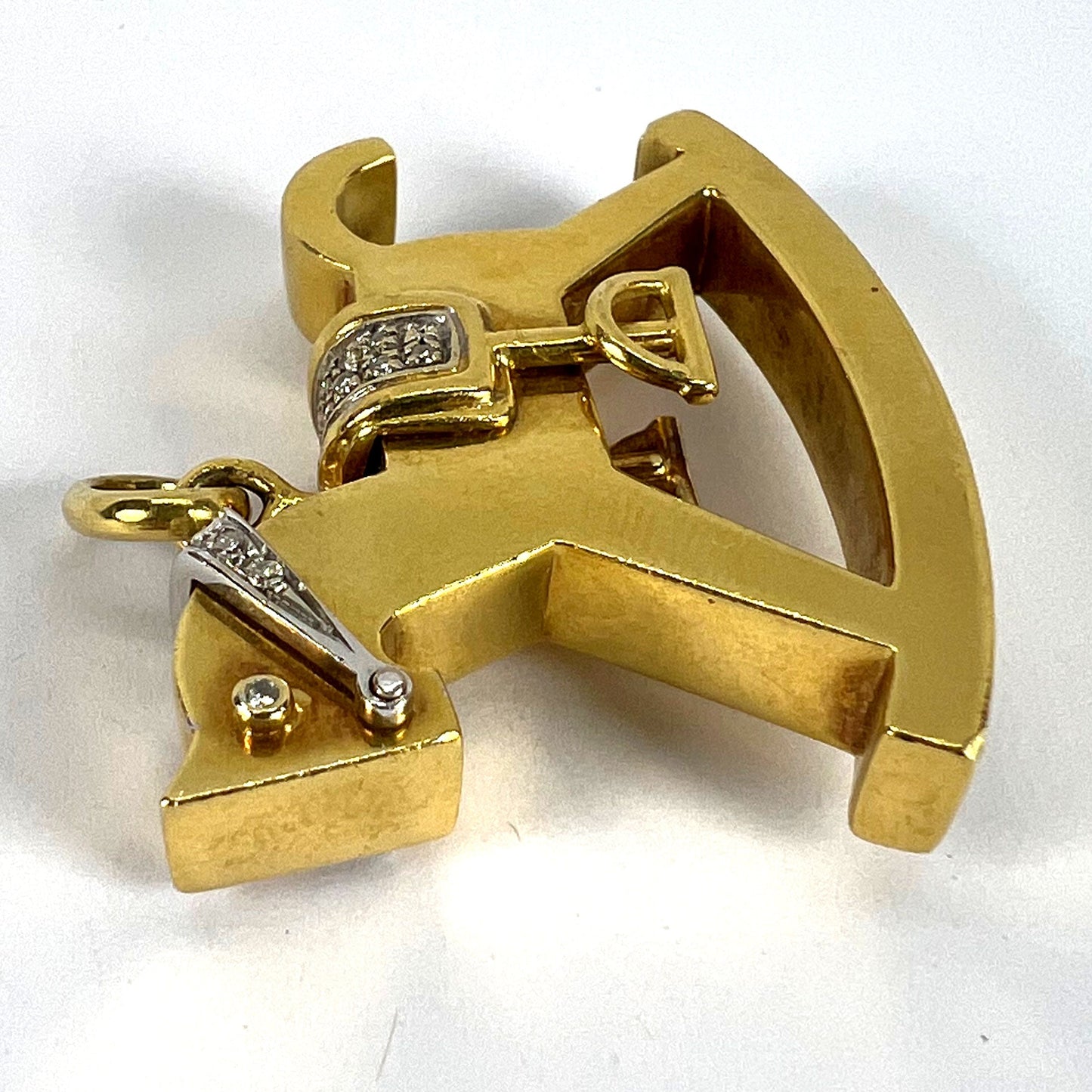 A yellow and white gold rockinghorse pendant with diamonds, on a white background