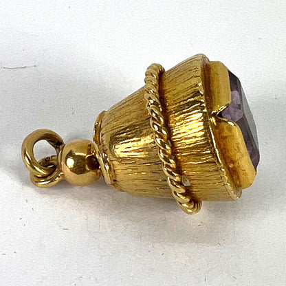 A yellow gold pendant with an amethyst set in the base, on a white background