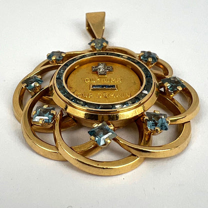 A yellow gold French QU'HIER QUE DEMAIN pendant with blue stones and diamonds, on a white background