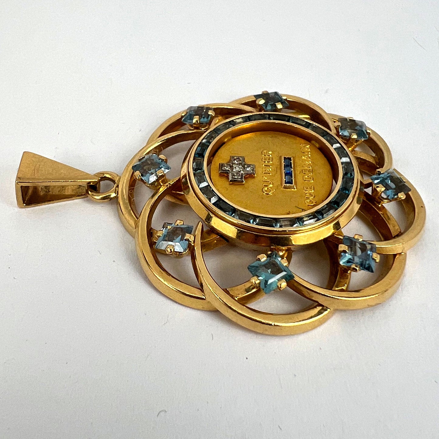 A yellow gold French QU'HIER QUE DEMAIN pendant with blue stones and diamonds, on a white background
