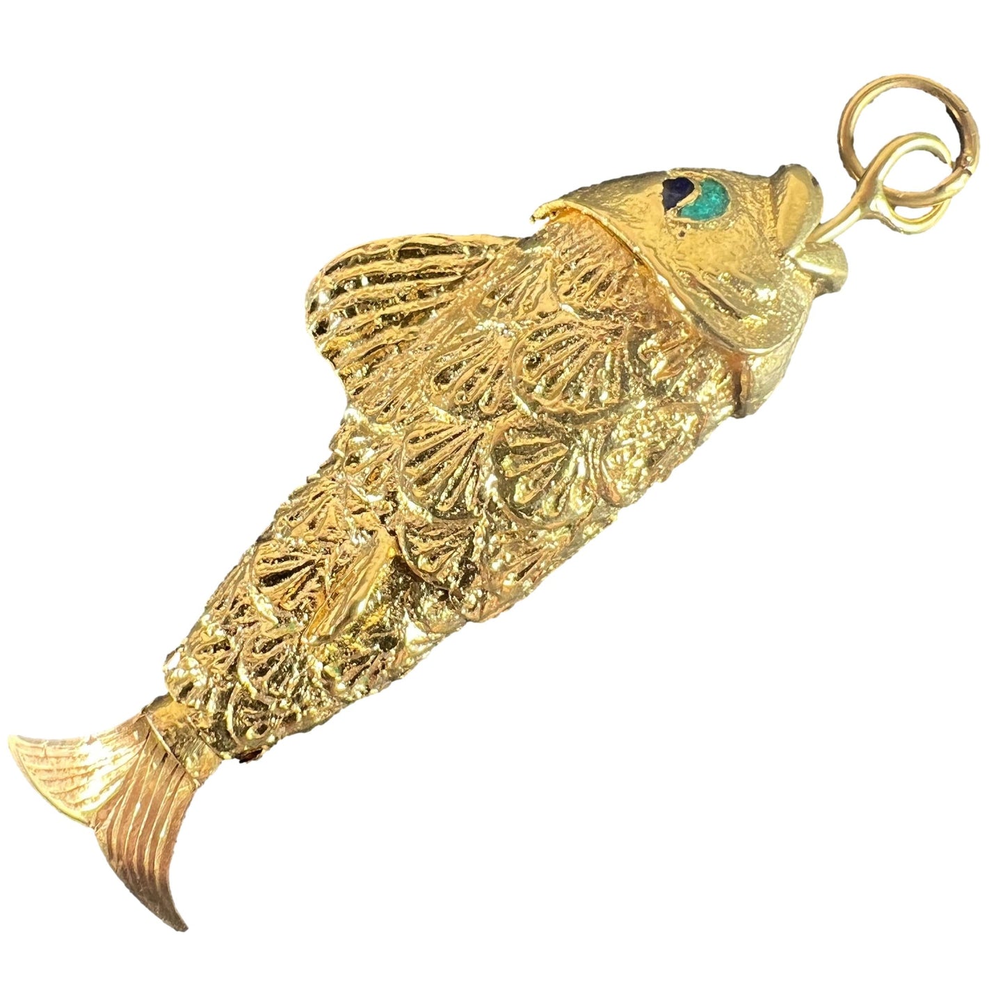 A yellow gold fish pendant with a green eye, on a white background
